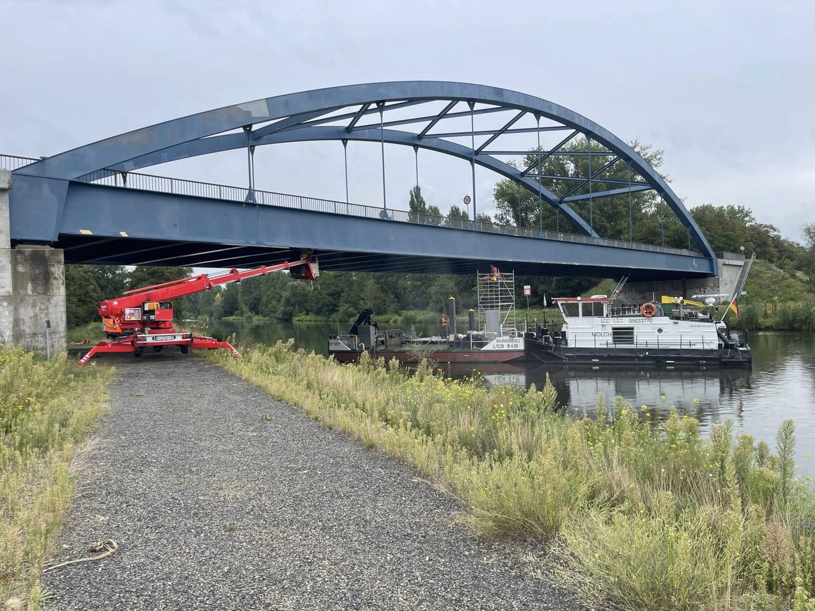 Stahlbogenbrücke über einen Kanal mit Hubarbeitsbühne